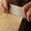 Person using a chisel on a wooden surface
