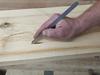 Person using a pencil on a wooden surface