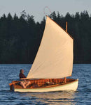 Sailboat with a white sail on a body of water with trees in the background